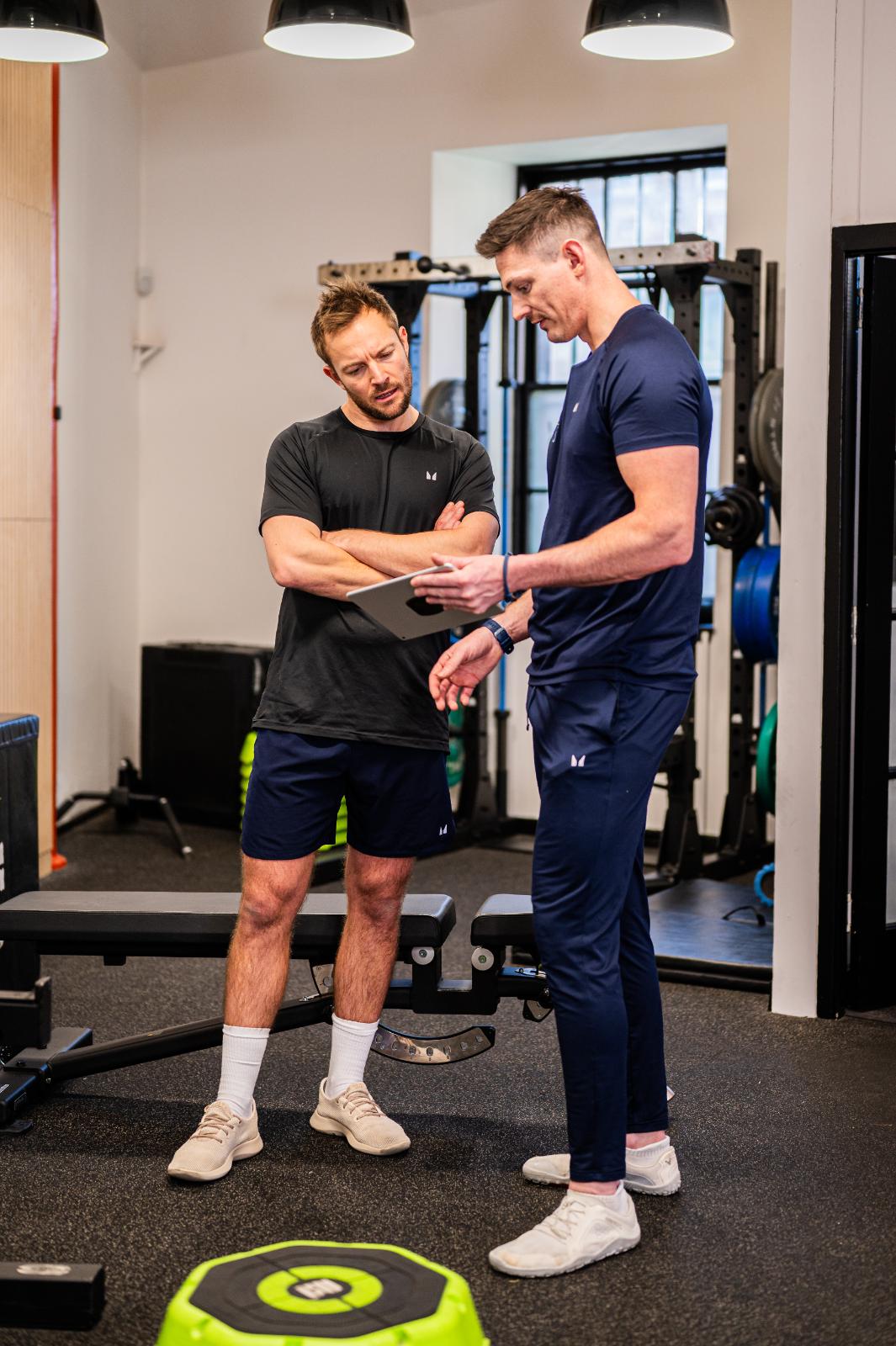 Stuart and Ross reviewing patient biometrics for personal training Edinburgh and rehab progress in Leith.