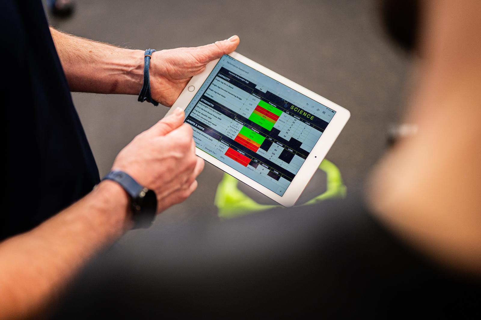Detailed strength capacity data on a tablet used for evidence-based personal training Edinburgh programs in Leith.
