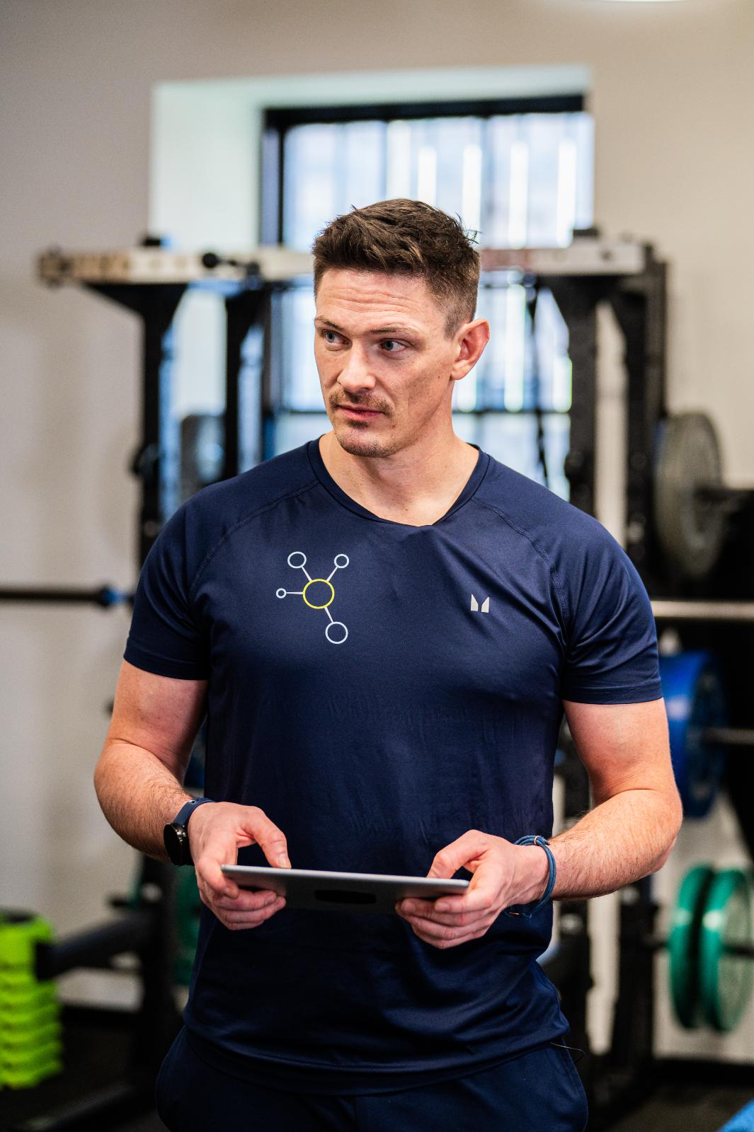 Health by Science practitioner reviewing digital rehabilitation data on a tablet during a personal training Edinburgh session.