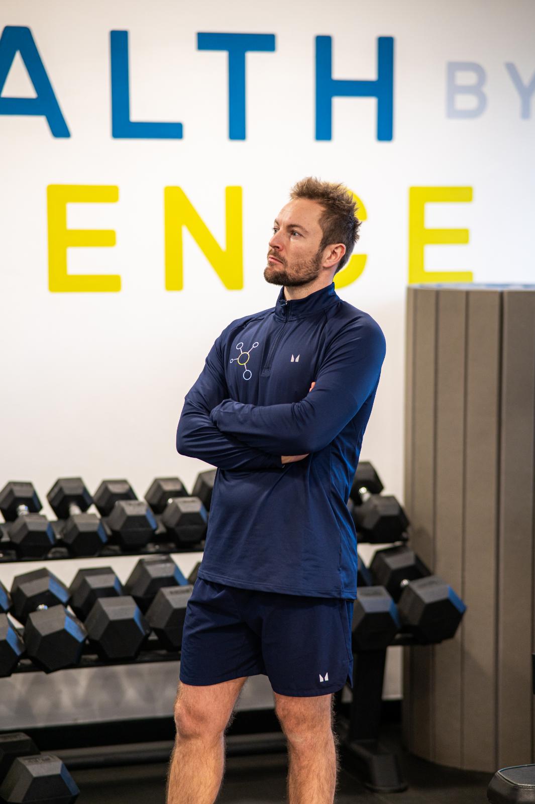 Professional Health by Science coach monitoring a personal training Edinburgh session in front of a clinical strength wall.