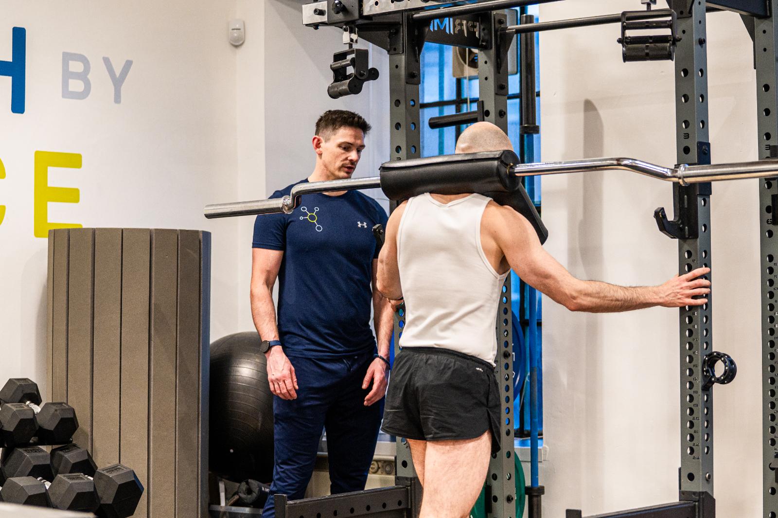 Health by Science practitioner monitoring lower body biomechanics during a clinical strength session in our Leith gym.