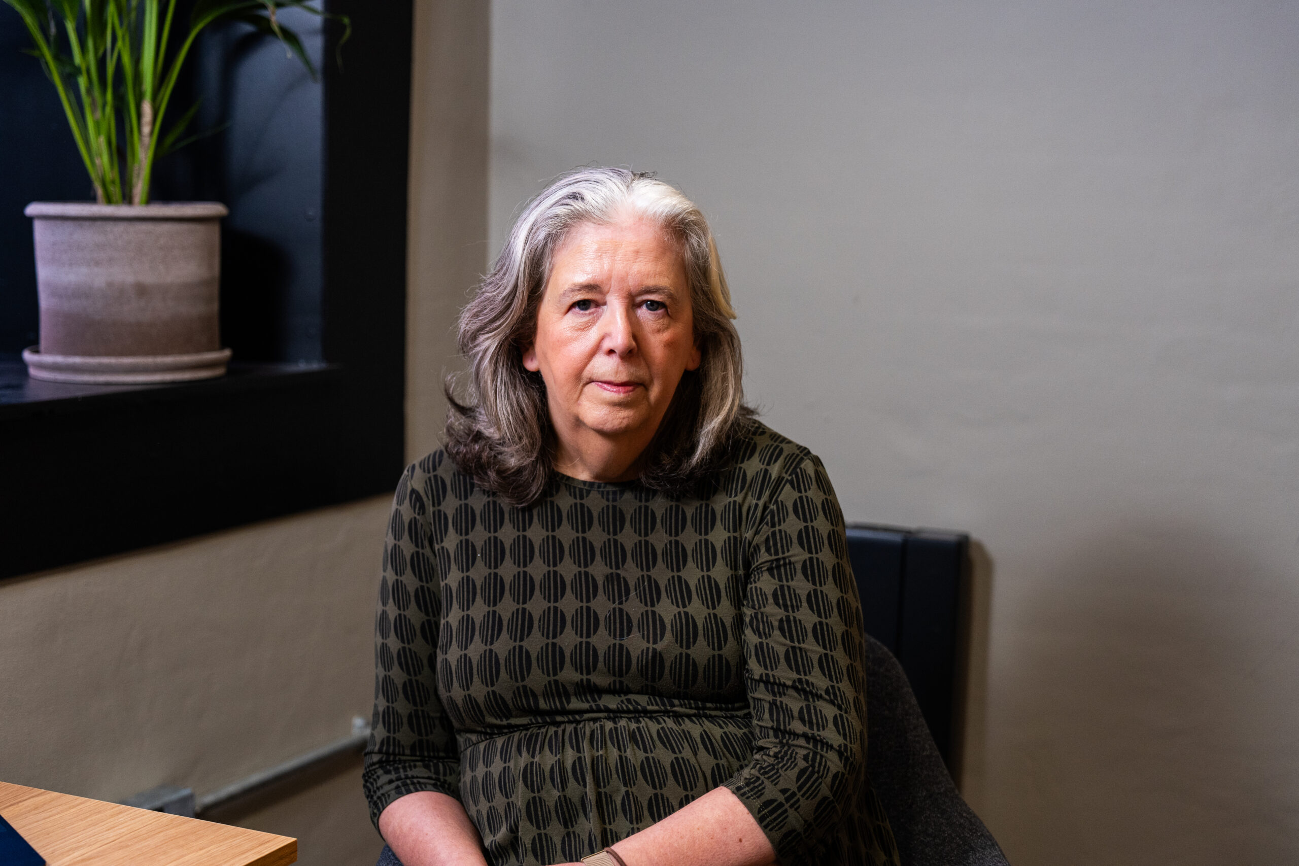 A professional female counsellor sitting in a calm, private office space for mental health support.