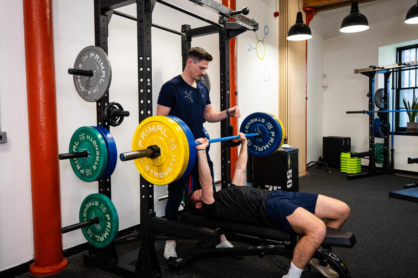 Clinical supervision of a barbell bench press for personal training Edinburgh to ensure optimal shoulder stability and form.