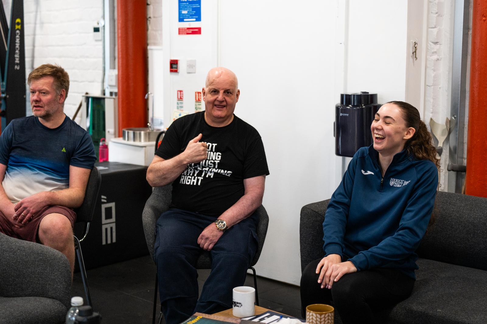 A group of diverse clients sitting together and laughing during a community-focused rehabilitation session.