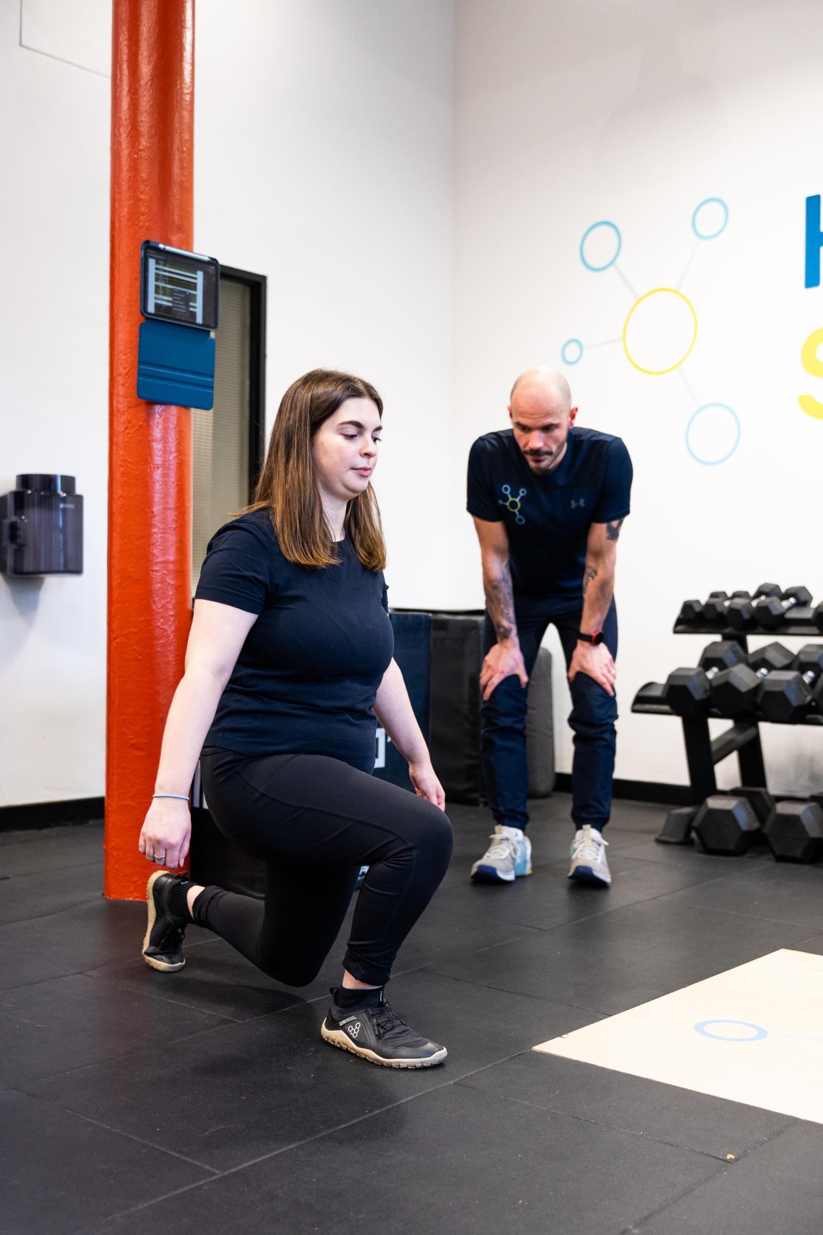 Specialist conducting a biomechanical movement screening to assess knee stability for a personal training Edinburgh client.