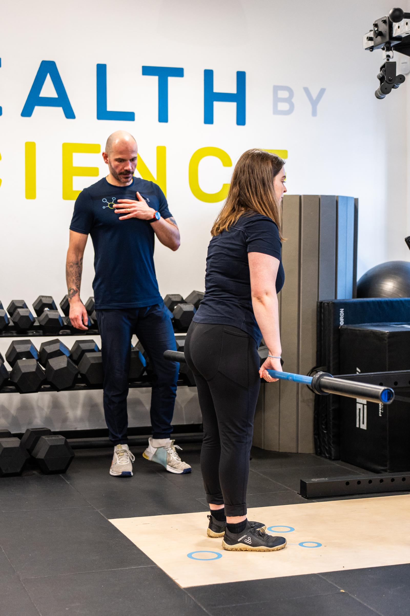 Specialist observing barbell deadlift technique to ensure safe lumbar mechanics for sports physiotherapy Edinburgh patients.