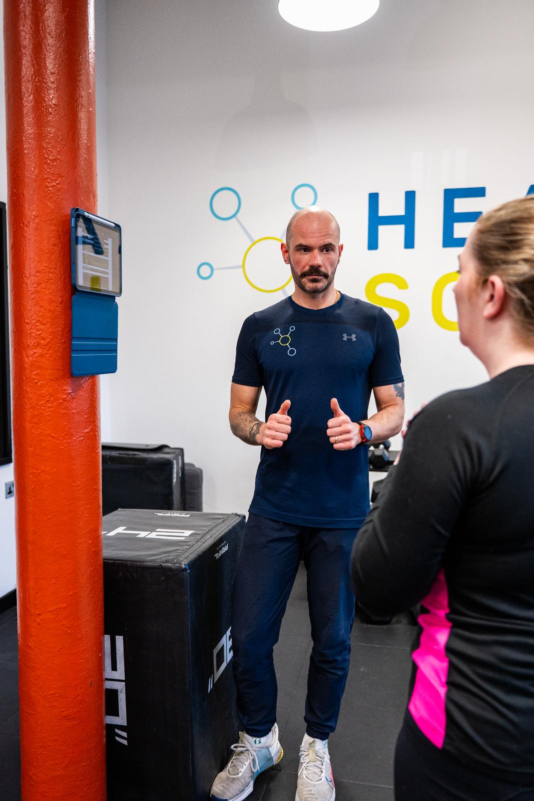 Professional Health by Science coach providing clinical feedback and encouragement during a personal training session.