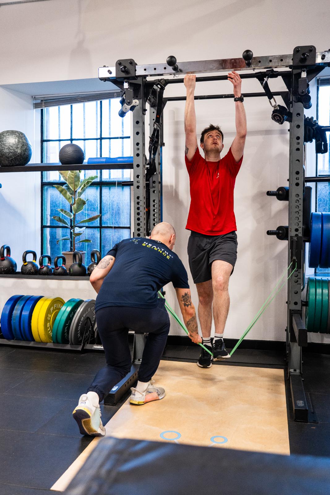 Health by Science personal trainer edinburgh conducting a band-assisted movement assessment to improve upper limb strength at our Leith clinic.