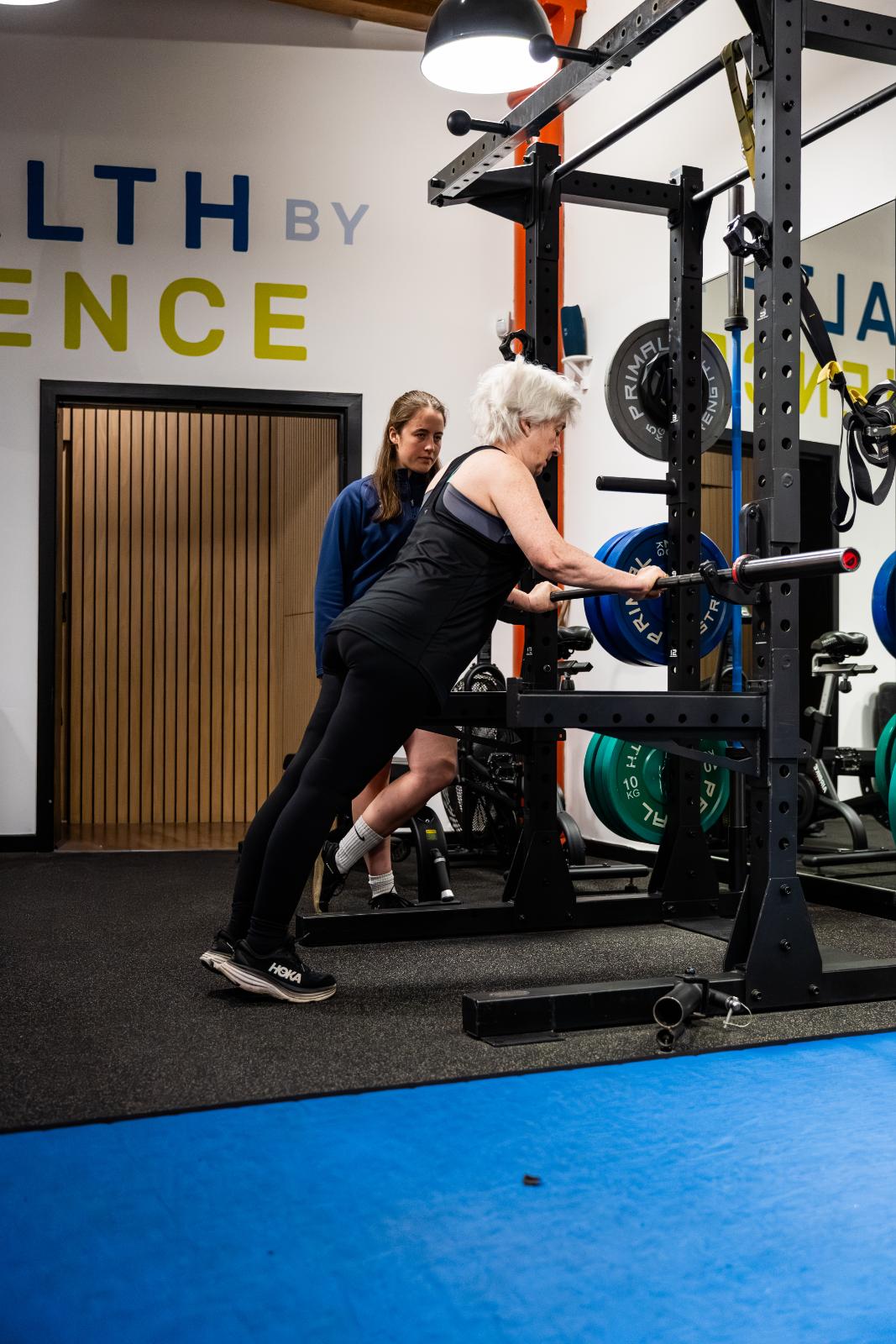 Clinical supervision of an incline push-up progression for a senior patient to improve functional upper body capacity.