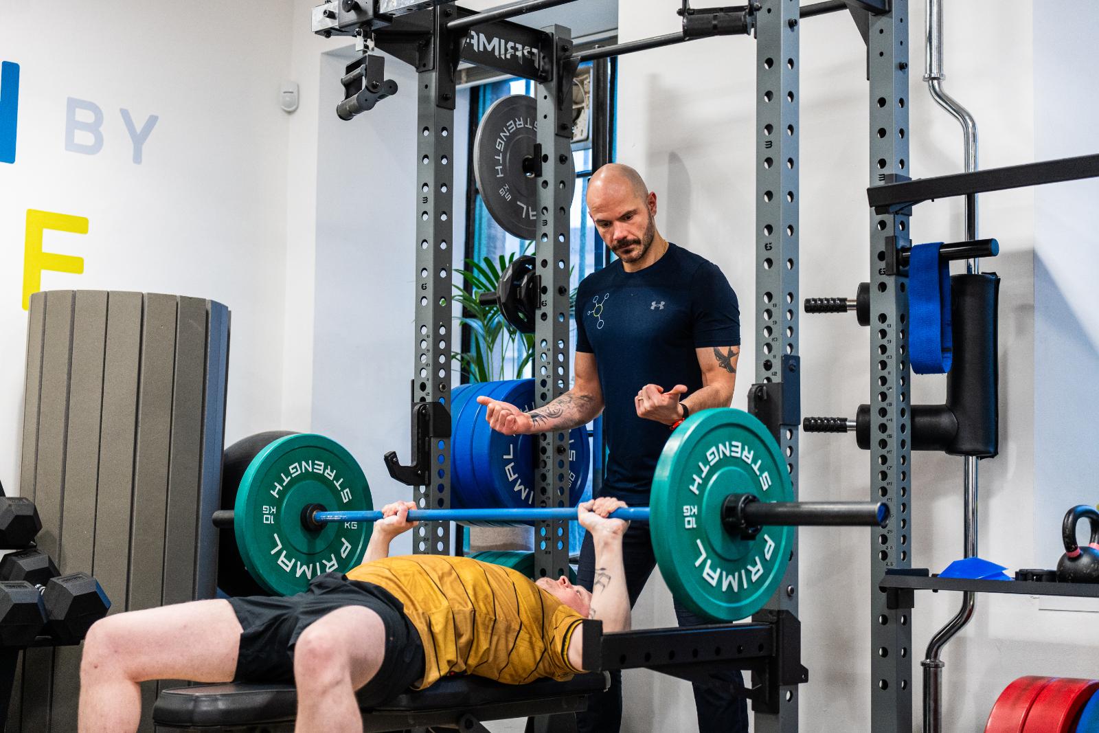 Health by Science specialist providing a safe spot and technical feedback for a barbell bench press during a personal training Edinburgh session.