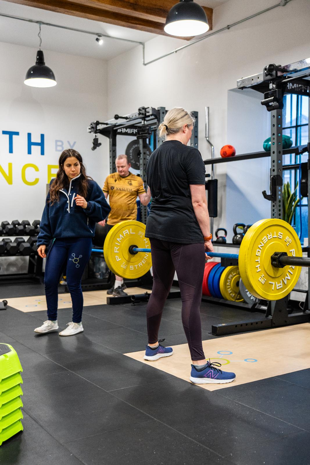 Clinical supervision of a barbell strength exercise at Health by Science Leith, specialising in data-driven injury recovery.