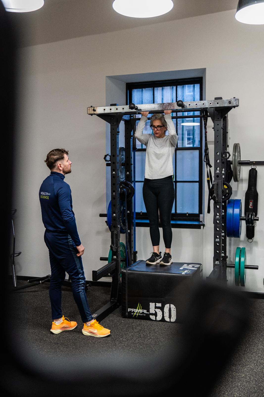 Professional monitoring of a pull-up progression for a senior patient to assess upper body strength and joint health.