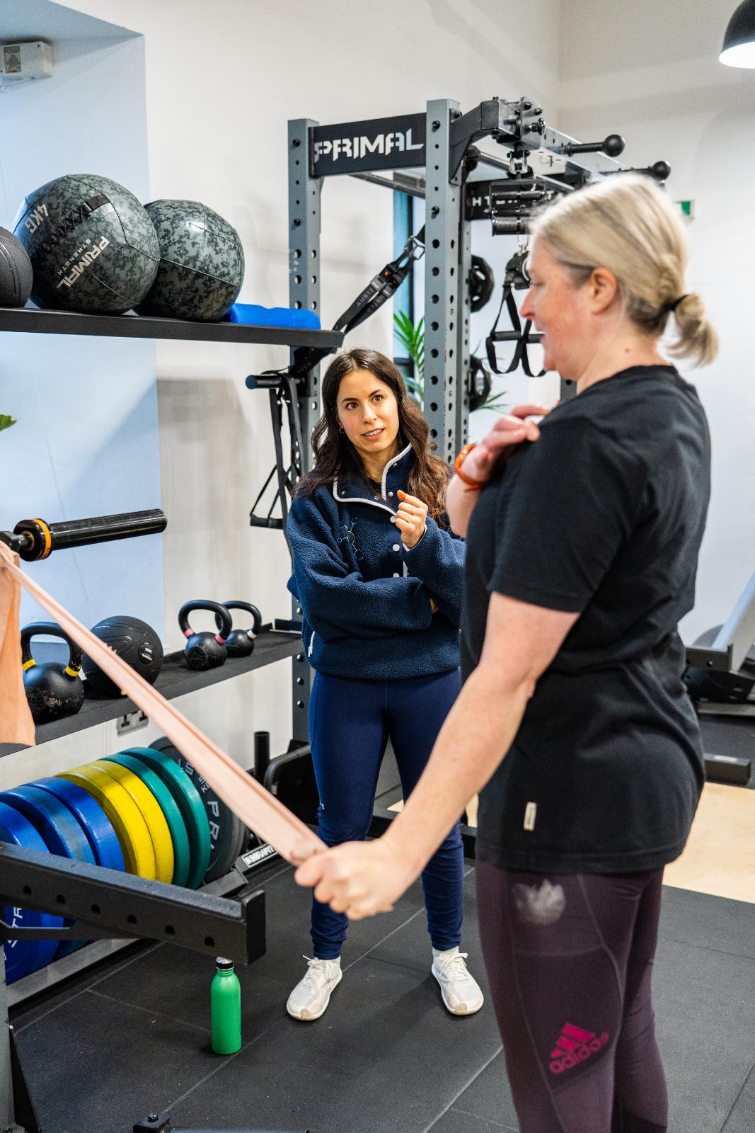 Health by Science specialist providing clinical movement instruction for a resistance band rehabilitation exercise in our Leith lab.