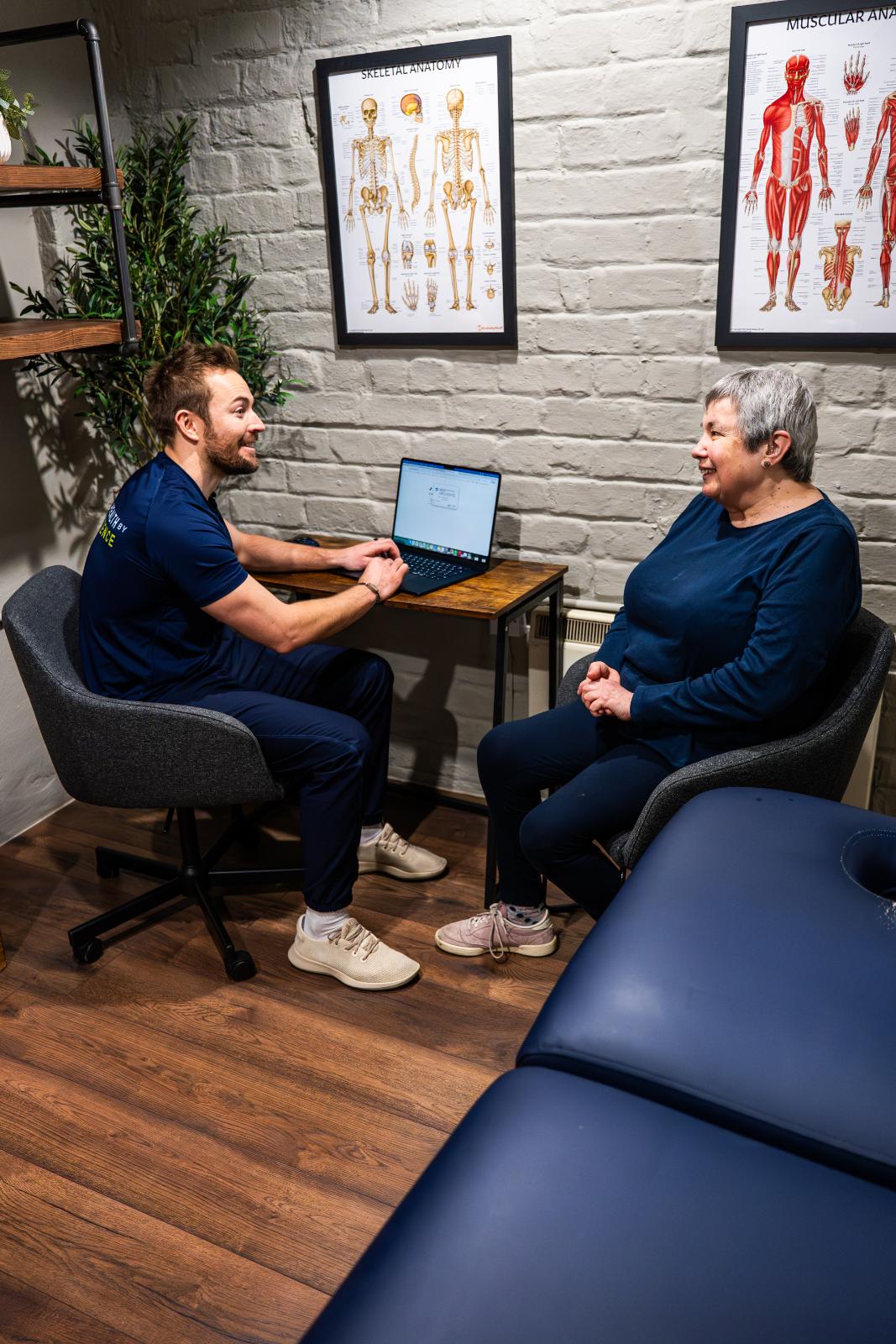 Professional clinical consultation between a Health by Science practitioner and a senior patient, reviewing progress on a laptop in Leith.