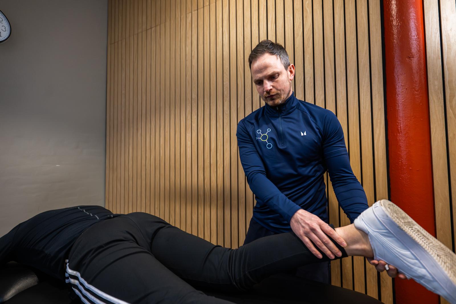 Specialist conducting a lower limb manual assessment to analyse ankle and foot biomechanics for a physiotherapy patient.