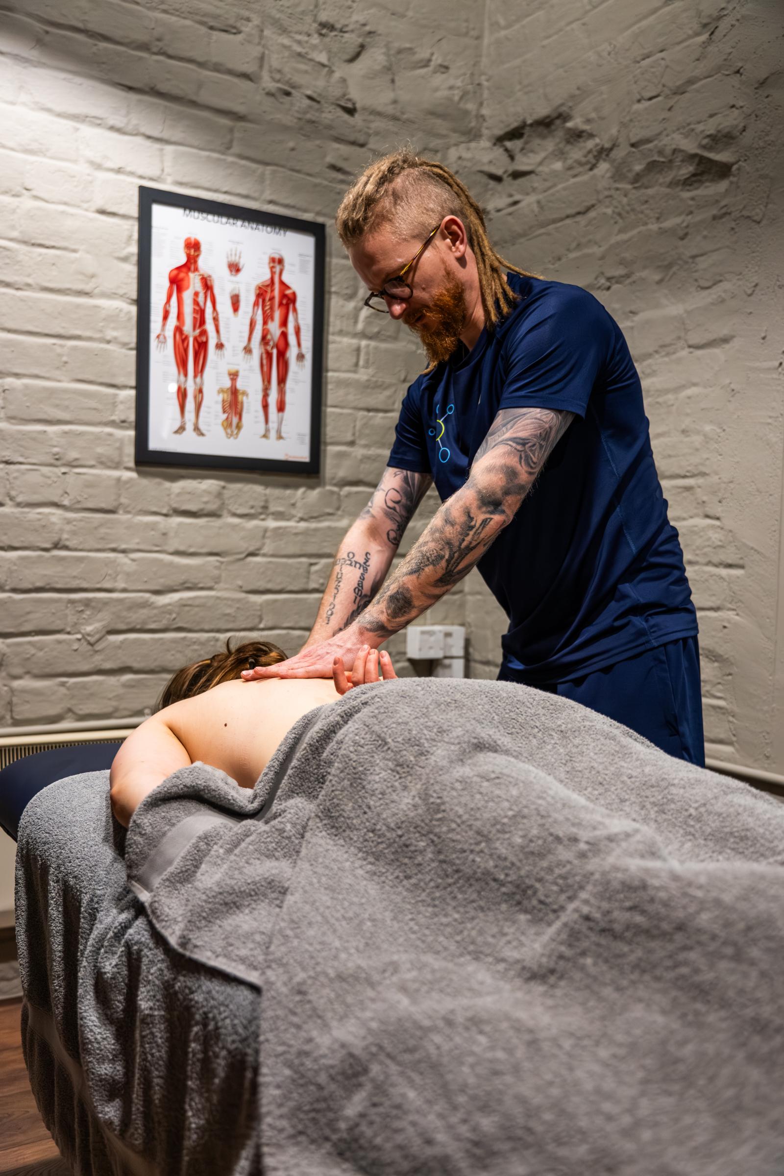 Practitioner providing data-driven soft tissue therapy to the mid-back area during a private treatment session in Leith.